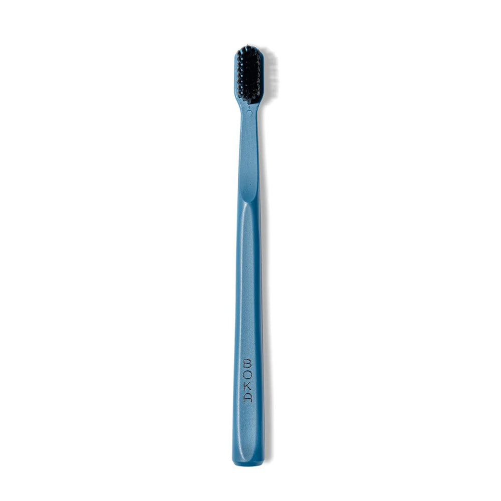 Classic Toothbrush in blue with activated charcoal bristles for a gentle clean, on white background.